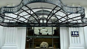 Une entrée d’immeuble dotée d’un auvent décoratif en métal, d’une façade en verre et d’une enseigne indiquant l’adresse.