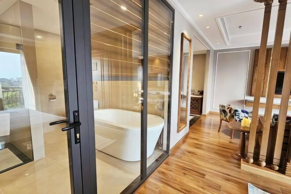 Ein modernes Badezimmer mit einer gläsernen Duschkabine, einer weißen Badewanne und einem Essbereich mit Holztisch und Stühlen.