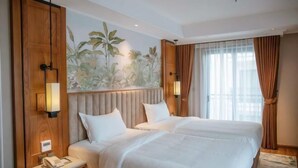Une chambre d’hôtel avec deux lits, une tête de lit en bois, un téléphone fixé au mur et une fenêtre avec des rideaux.
