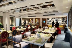 Un restaurante con varias mesas y cabinas, un diseño moderno en el techo y un cuadro abstracto grande en la pared.
