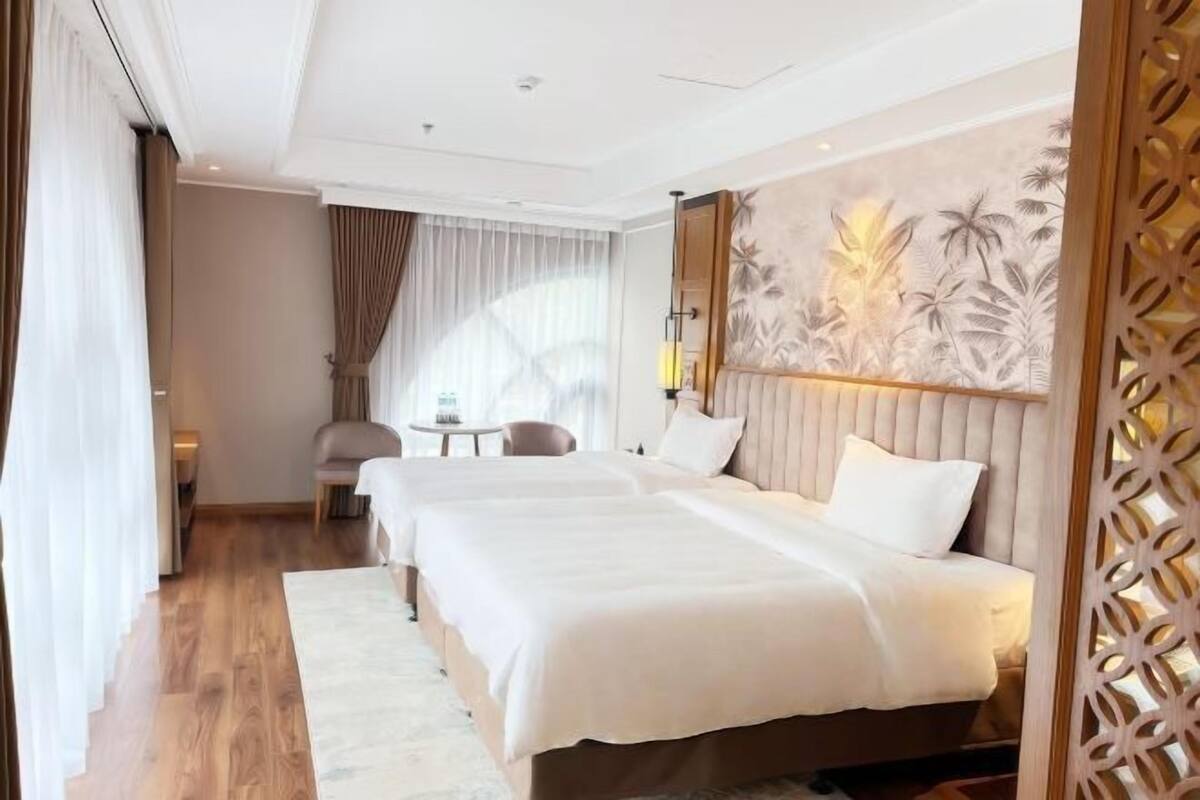 Ein Hotelzimmer mit einem großen Bett, einem kleinen Tisch, einem Stuhl und einer Wandverzierung.