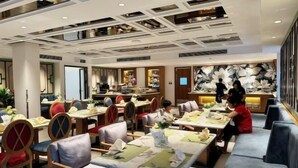 Un restaurant moderne avec un plafond haut, de nombreuses tables et des espaces de repos confortables.