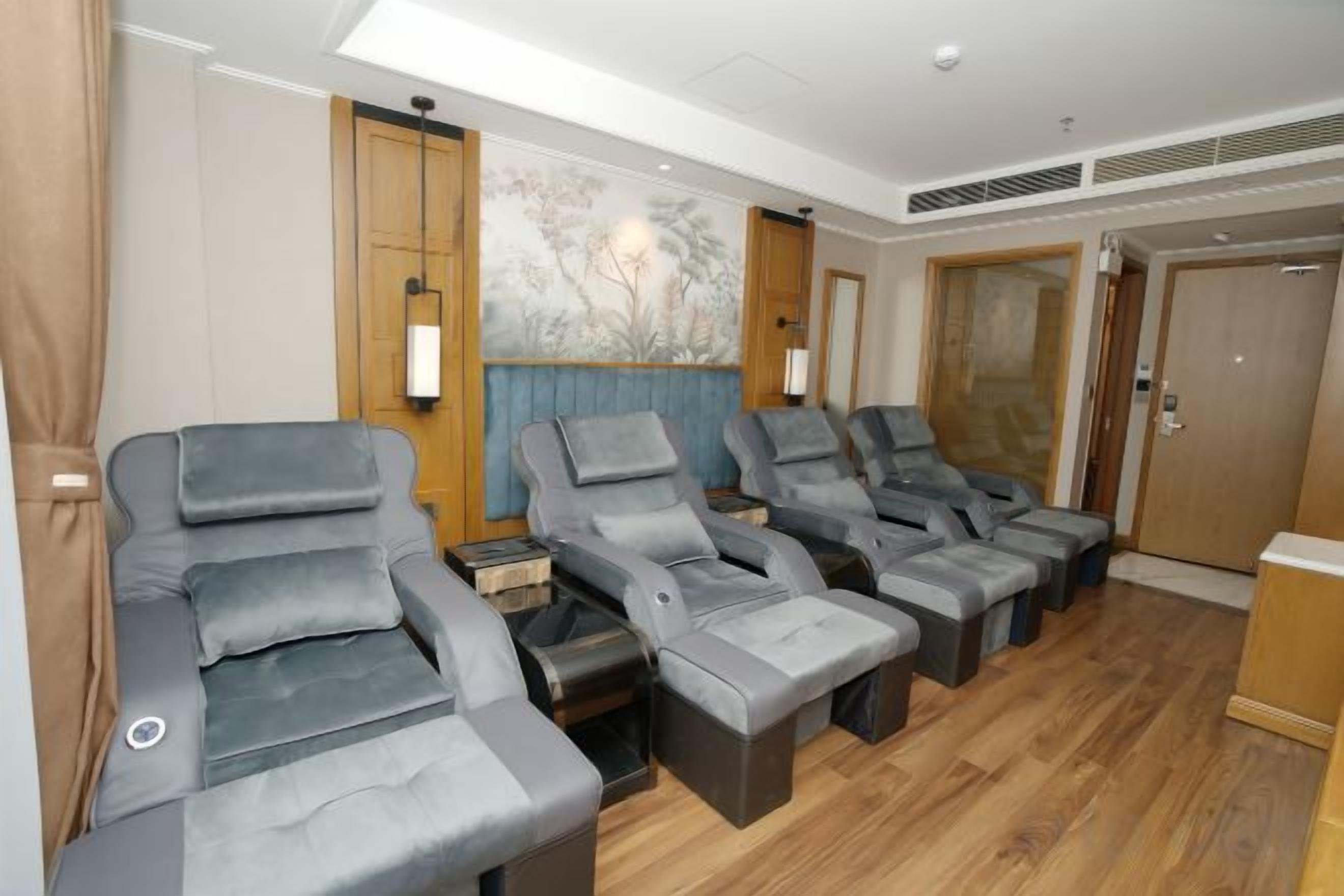 A room with multiple reclining massage chairs, a wooden floor, and a large painting on the wall.