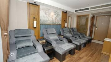 A room with multiple reclining massage chairs, a wooden floor, and a large painting on the wall.