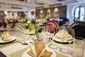 Une table à manger dressée avec des assiettes, des verres et un vase rempli de fleurs.