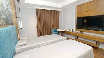 A hotel room with two beds, a desk, a chair, a large window, and a painting on the wall.