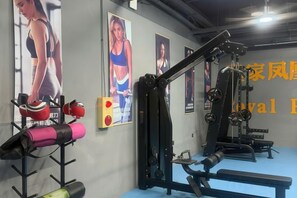 Une salle de sport équipée de matériel d’exercice, avec des affiches aux murs et un sol bleu.