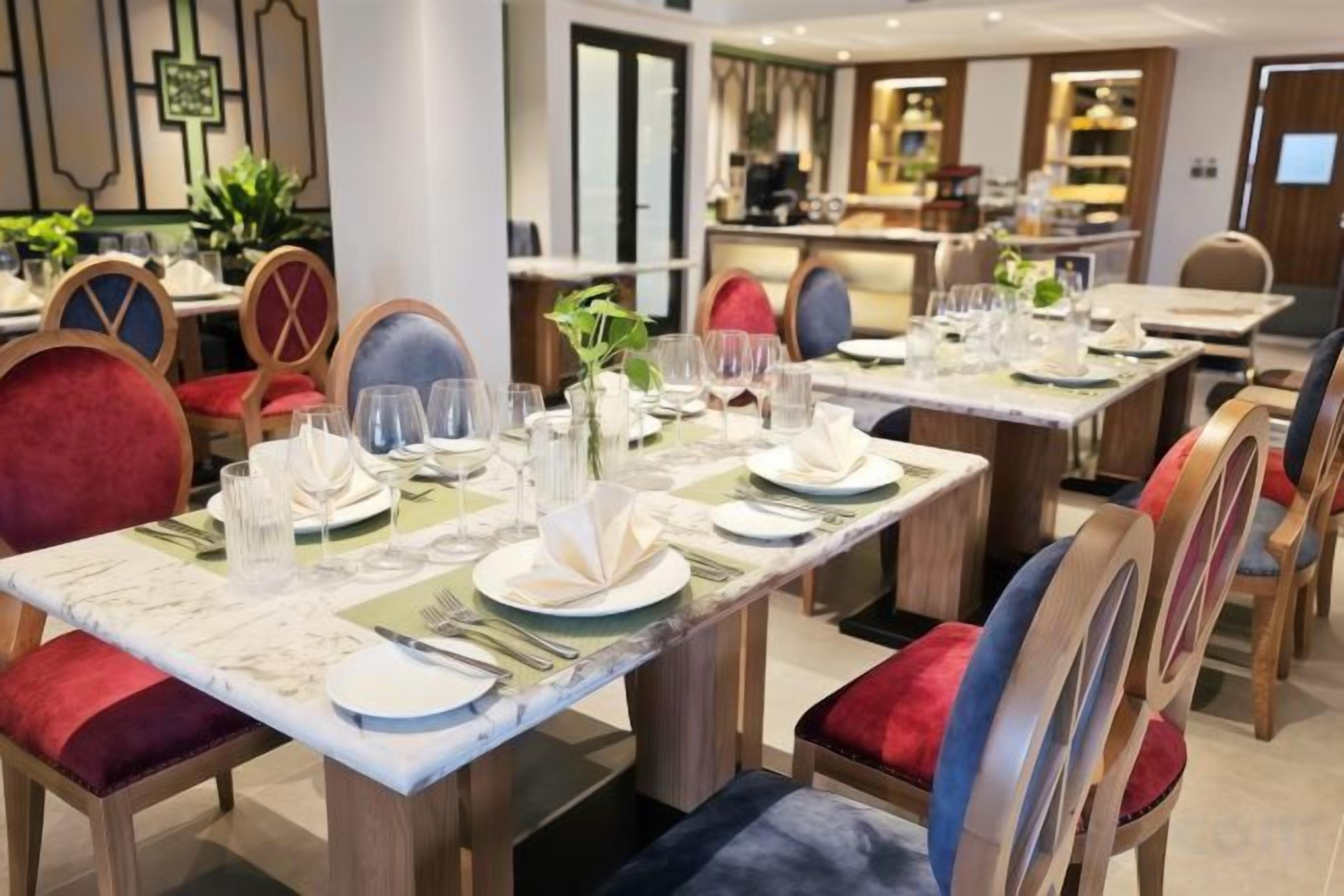A dining area with tables set for multiple guests, chairs with cushioned seats, and a modern interior design.