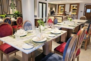 A dining area with tables set for multiple guests, chairs with cushioned seats, and a modern interior design. - Royal Phoenix Hotel Bac Ninh (Bac Ninh)