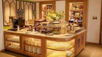 A hotel reception area with a counter, coffee machines, and a display of various items.