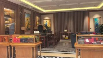 A hotel lobby with a checkered floor, wooden furniture, and artwork on the walls.