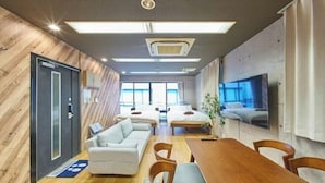 Une chambre d’hôtel moderne avec un mur d’accent en bois, un grand lit, un canapé, une table à manger et un téléviseur fixé au mur.