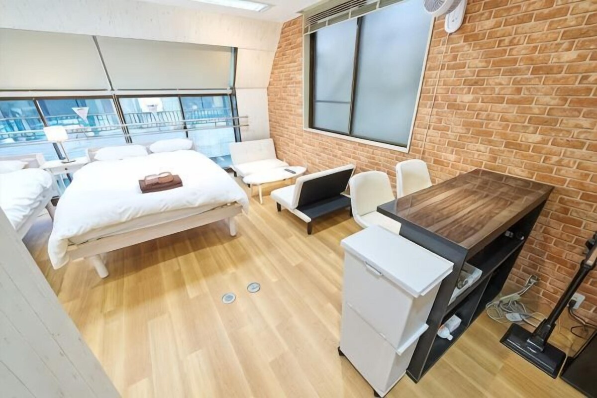 A modern hotel room with a bed, seating area, and a large window.