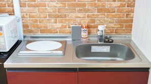 A kitchen with a brick wall, a microwave, a scale, a kettle, and a sink. - 4 min walk to Shinbashi Station, Ginza, Imperial Palace, Tokyo Tower / Max6 (Tokyo)