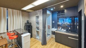 Une chambre d’hôtel compacte comprenant un coin cuisine, un petit espace repas et une cabine de douche.