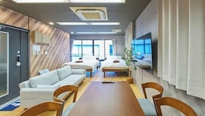 Une chambre d’hôtel moderne avec un mur en bois, une grande fenêtre, un canapé, une table à manger et un téléviseur.