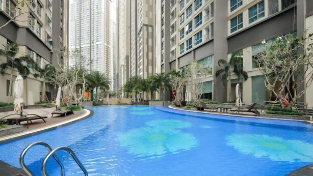 A swimming pool surrounded by high-rise buildings, with lounge chairs and palm trees. - Landmark Plus Center Suite (Ho Chi Minh City)