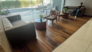 A modern lobby with a wooden floor, a sofa, a coffee table with a plant, and a seating area with chairs. - Landmark Plus Center Suite (Ho Chi Minh City)