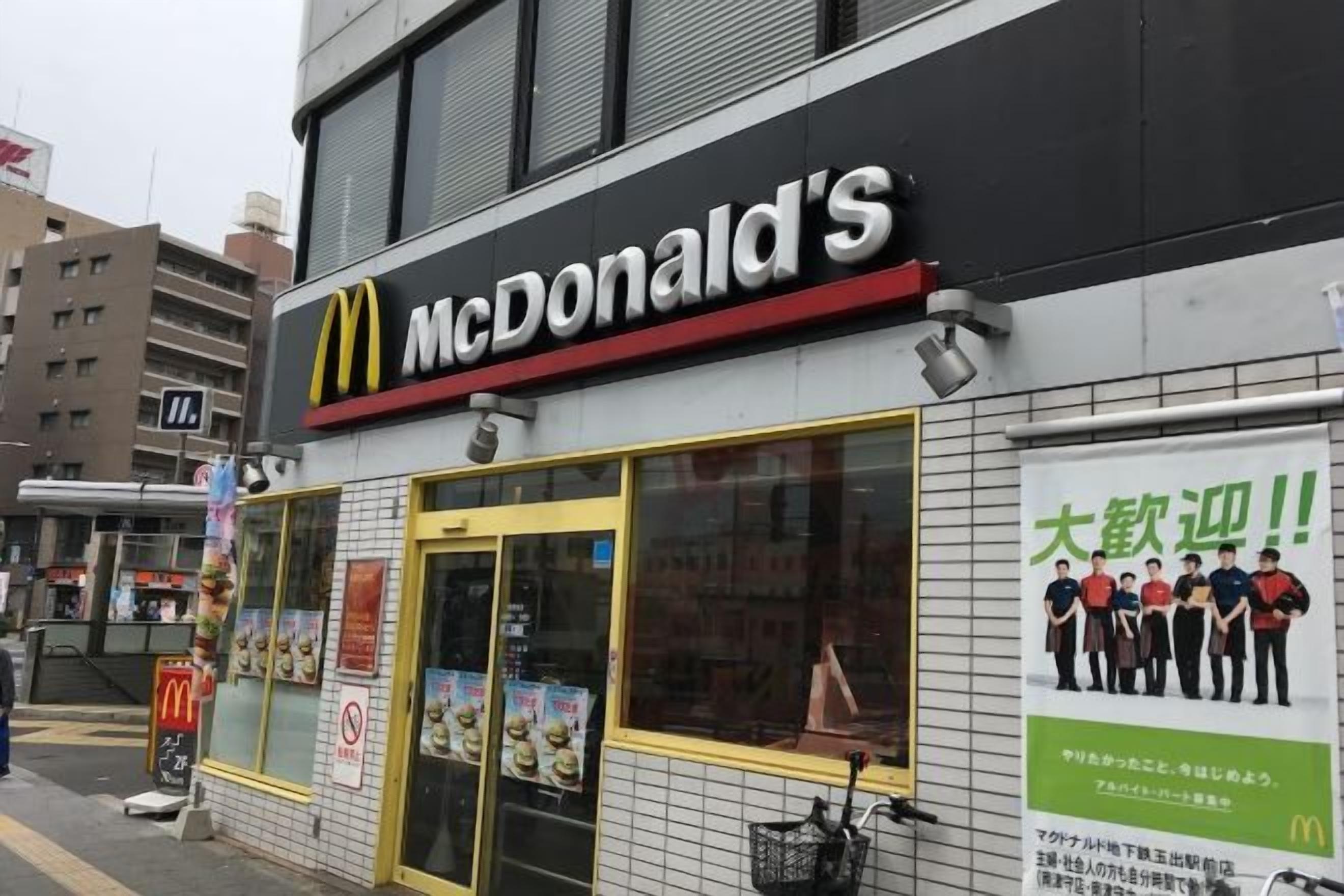 A McDonald's restaurant with a large glass window, a signboard, and a poster on the wall.