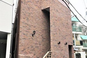 A brick building with a visible staircase and a light fixture on the exterior wall. - STAYBB OSAKA Tamade｜Free WIFI｜8mins from Namba (Osaka)