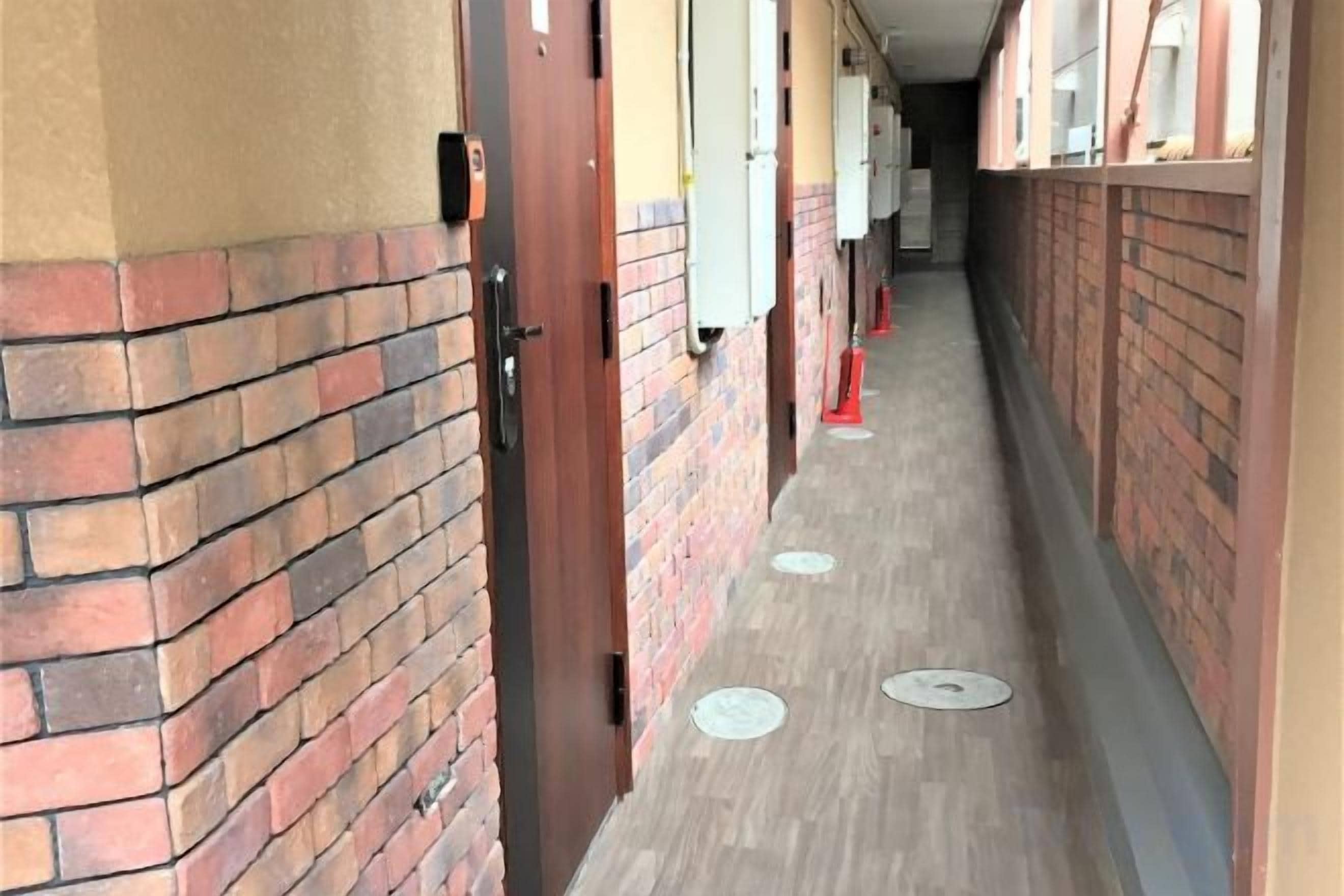 A corridor with brick walls, doors, and windows.