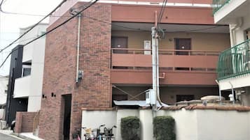 Un immeuble résidentiel à plusieurs étages, doté de balcons, d’une façade en briques et d’une entrée sécurisée par un portail.