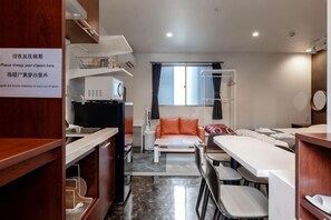 Ein kompaktes Hotelzimmer mit einer Küchenzeile, einem Schlafsofa, einem Esstisch und einem kleinen Fernseher.