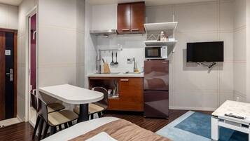 Une chambre d’hôtel compacte comprenant un coin cuisine, un espace repas, un lit et un téléviseur.