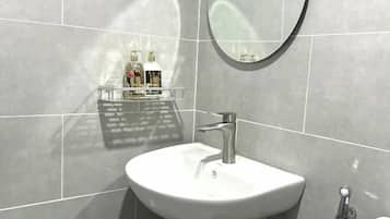 A bathroom with a white sink, a mirror, and a shelf with toiletries.