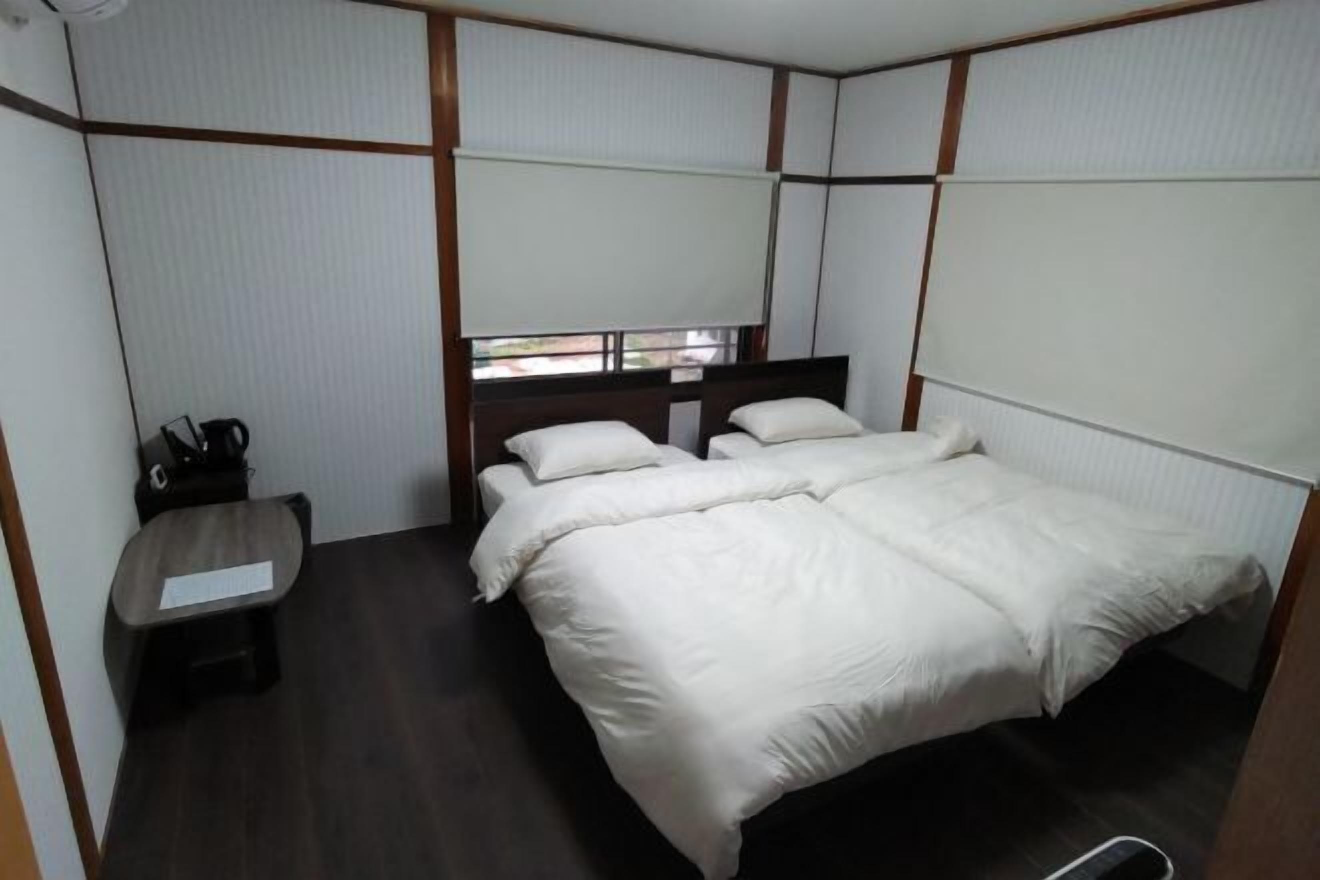 A room with a bed, a small table, and a window.