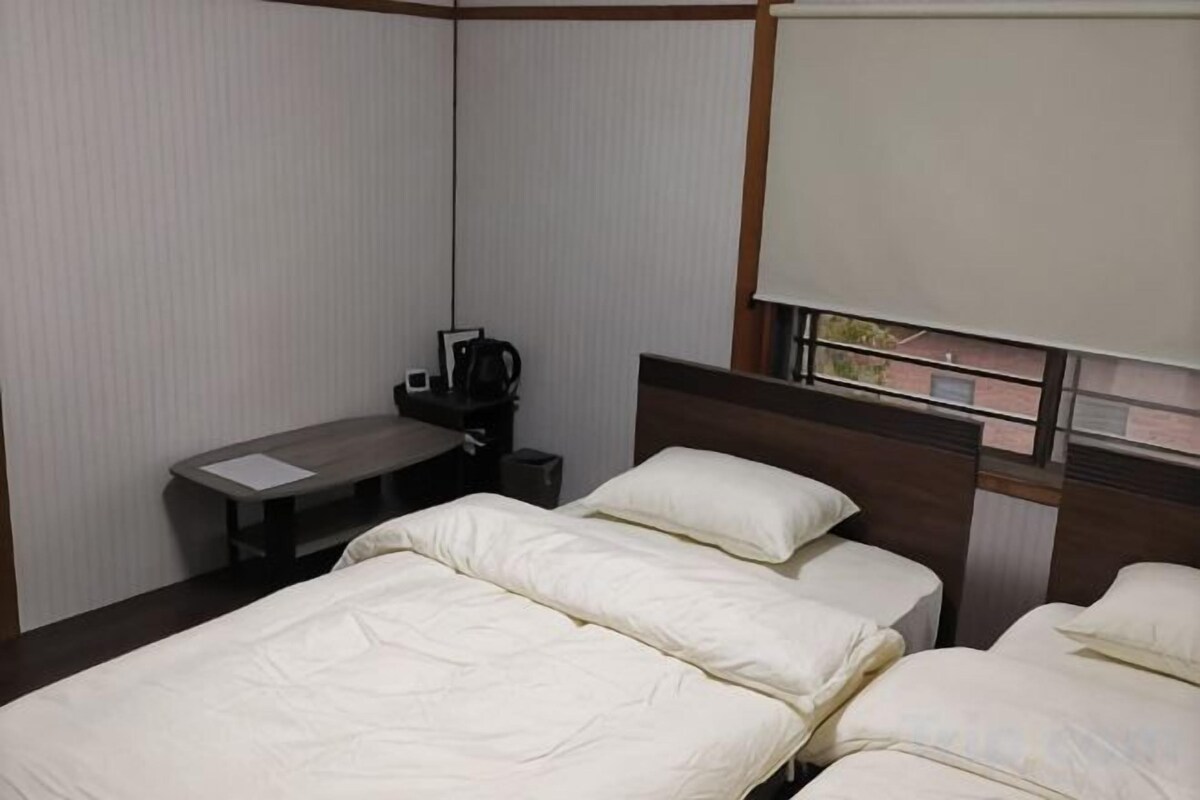 A hotel room with a bed, a desk, and a window.