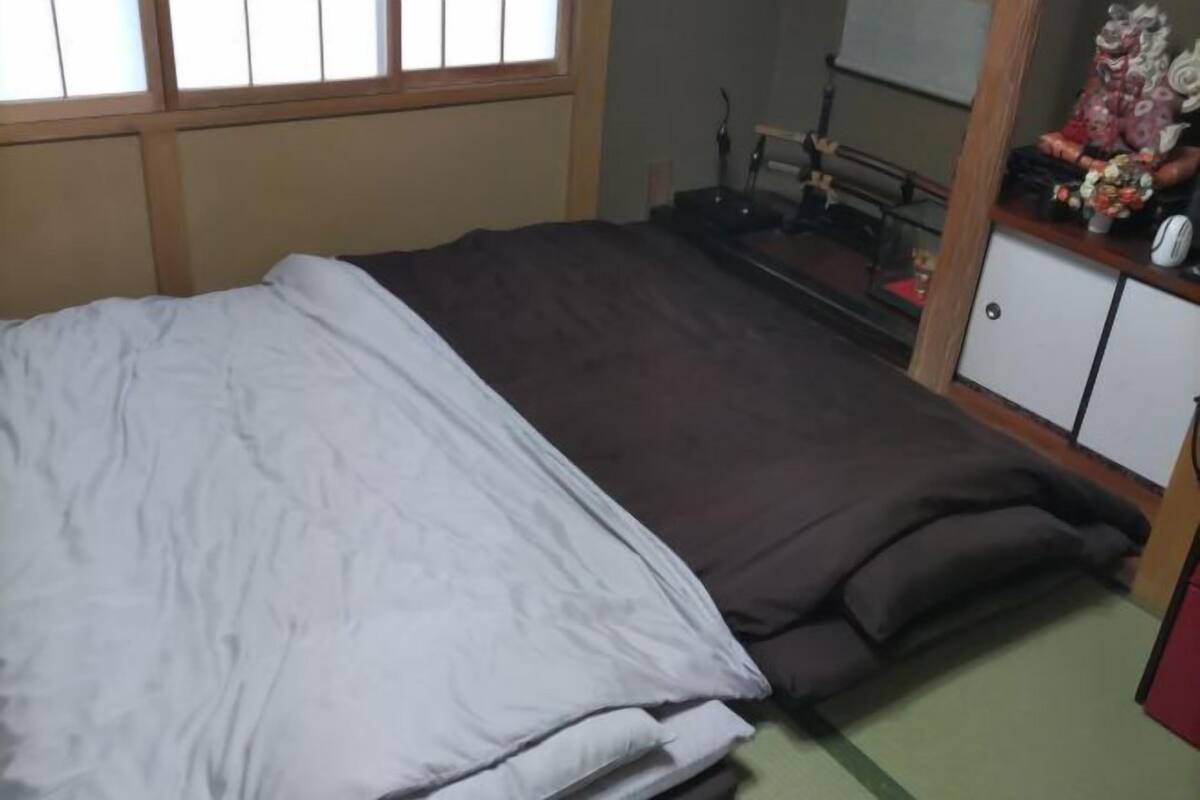A bedroom with a bed, a window, a desk with a chair, and a cabinet.