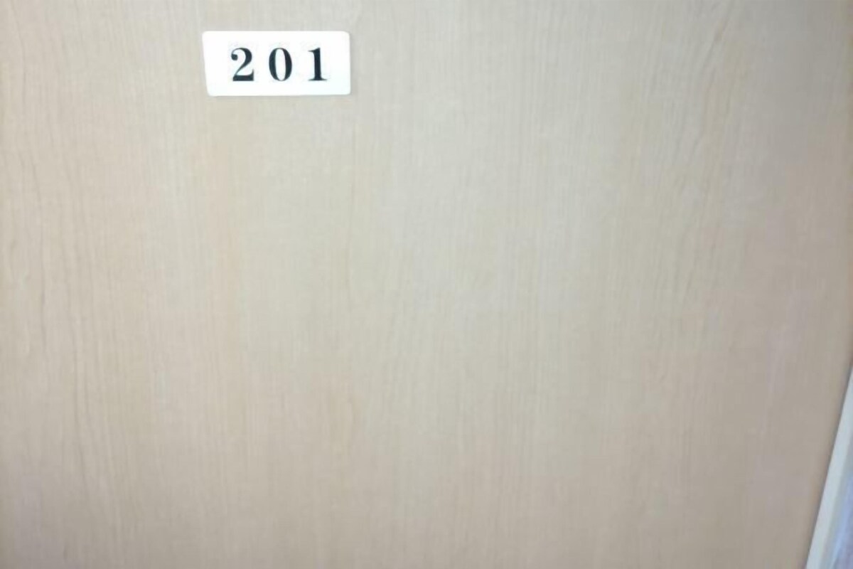 Un mur sur lequel est affiché un panneau blanc portant le numéro « 201 ».