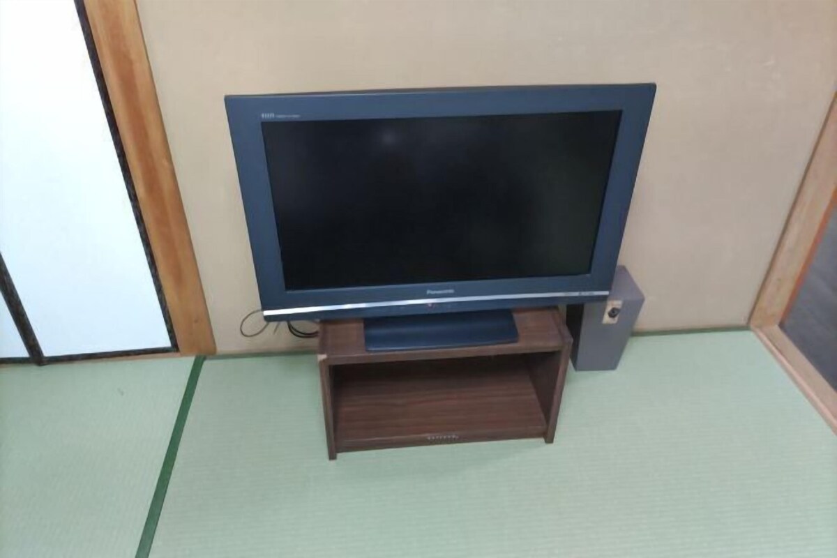 Ein Flachbildfernseher auf einem Holzständer in einem Raum mit Tatami-Boden.