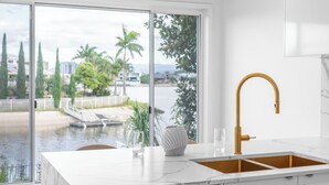 Una cucina moderna con lavastoviglie integrata, un rubinetto dorato e vista sul lungomare.