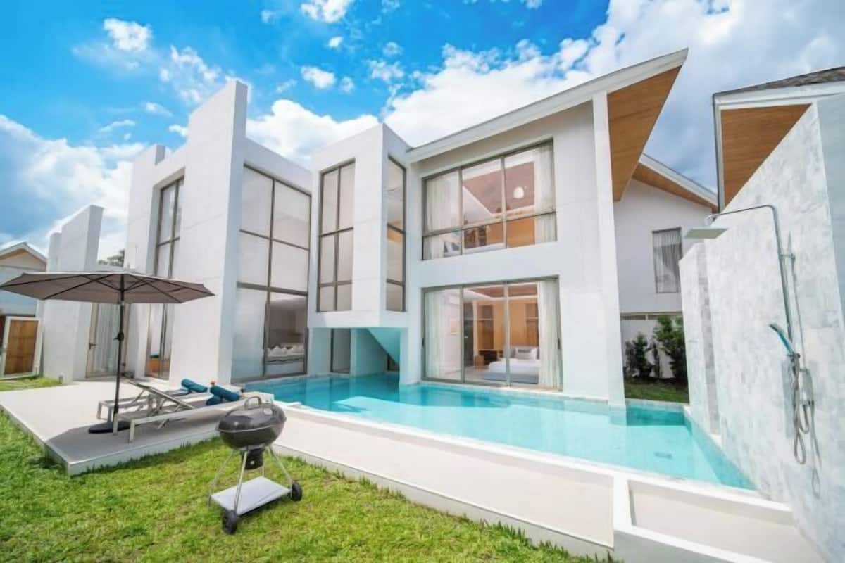 A modern house with a swimming pool, a barbecue, and a patio area.