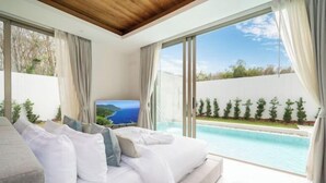Quarto com uma cama grande, televisão e vista para uma piscina.