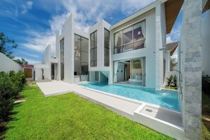 Una casa moderna con piscina, ventanas amplias y un césped bien cuidado.