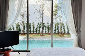 A bedroom with a large window, a bed, and a TV on a stand. - 4 Bedroom Modern Pool Villa Resort near Bangtao Beach Warm Plus (Phuket)
