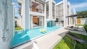 Uma casa moderna de dois andares, com piscina, área de estar ao ar livre e churrasqueira.