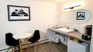 Un baño moderno con lavamanos, espejo y dos sillas.