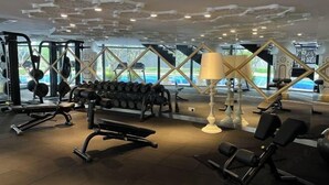 Ein Fitnessstudio mit verschiedenen Trainingsgeräten, darunter Kurzhanteln, Bänke und Kraftgeräte.