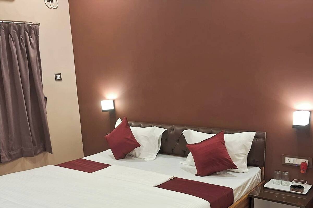 Una habitación de hotel con una cama grande, dos mesitas de noche y una cortina.