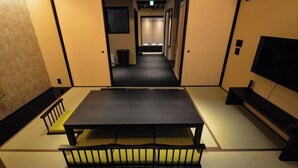 Une pièce de style japonais traditionnel, avec un sol recouvert de tatamis, une table basse et un futon servant de lit.