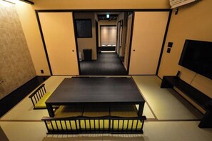 A traditional Japanese-style room with tatami flooring, a low table, and a futon bed.