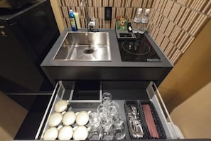 A modern kitchen with a stainless steel sink, a built-in stove, and a drawer with glasses and cutlery.