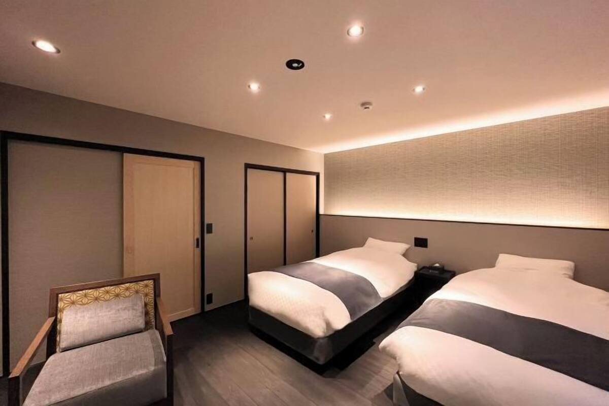 A hotel room with a bed, a chair, and a wardrobe.