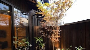 Un bâtiment moderne avec une façade en bois, une porte en verre et un petit jardin agrémenté de différentes plantes.