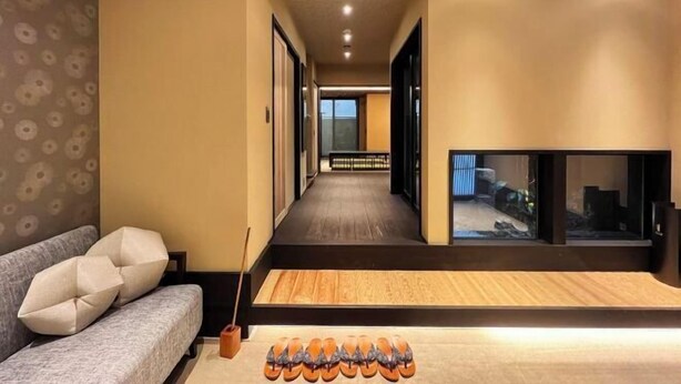 Un couloir avec un canapé, une table en bois et un porte-chaussures.