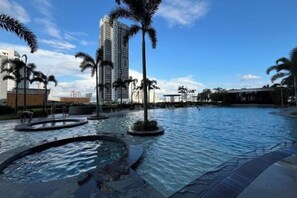 Una piscina con palmeras y un edificio alto al fondo.